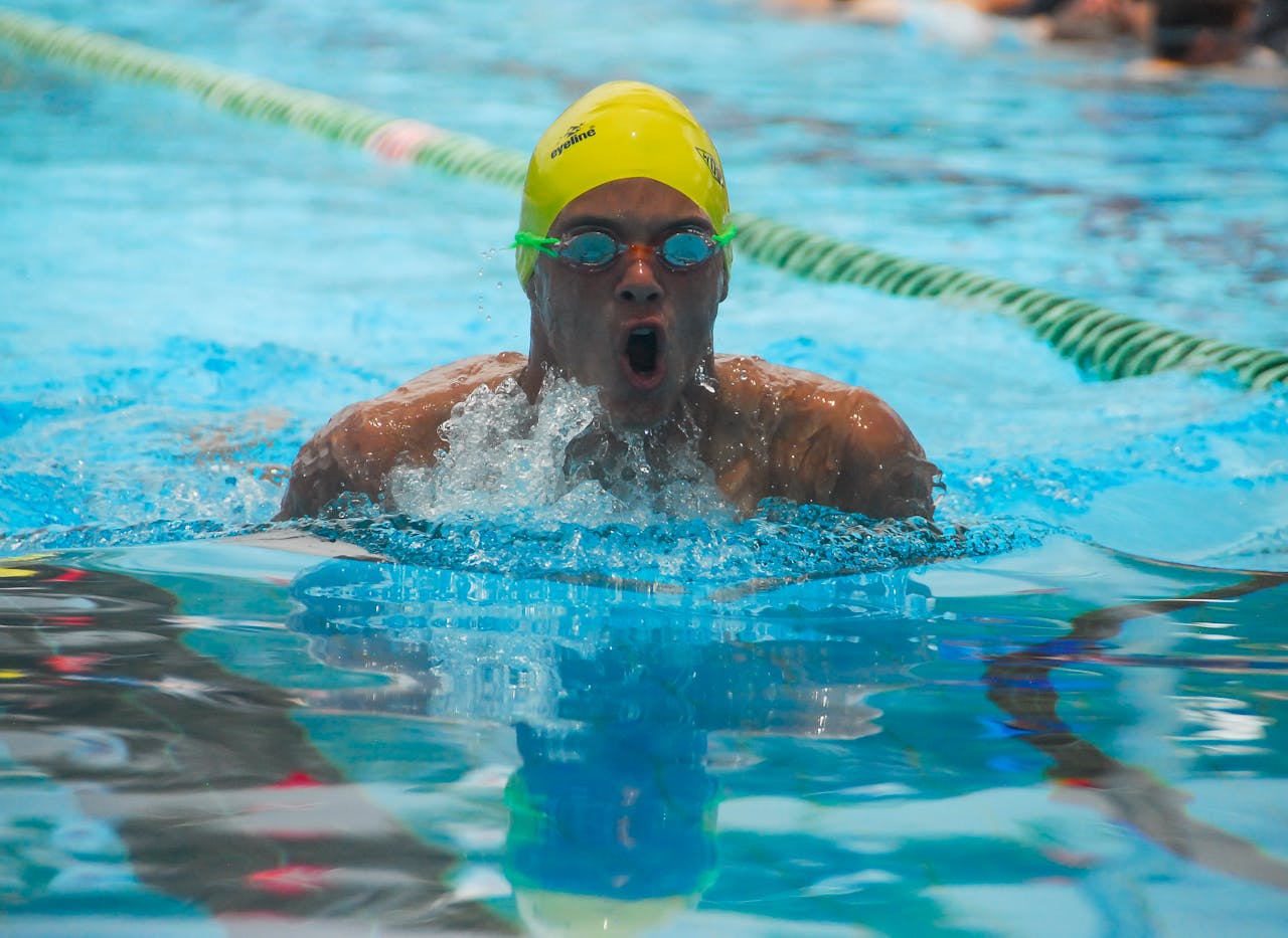 about-us-01 Swimmer competes with intensity in a sunny outdoor pool setting.